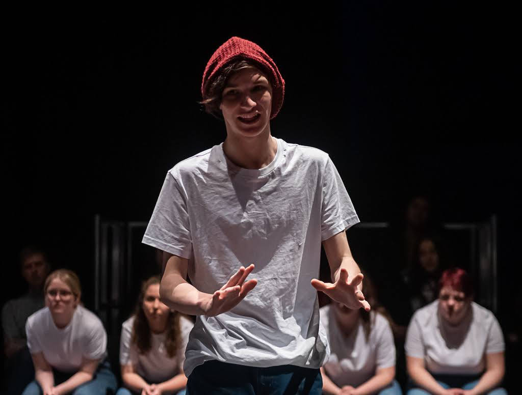 A teenager in a white t-shirt and red hat