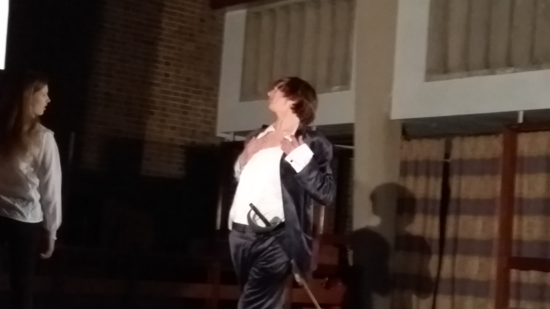 a teenager with a sword in a velvet suit clutching his chest