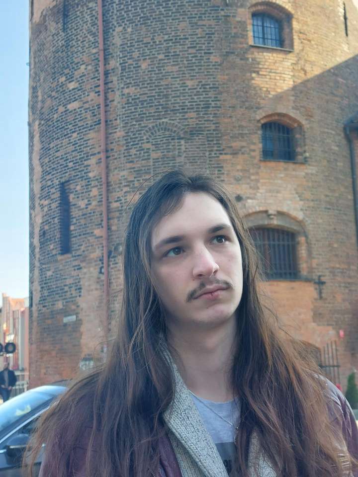 A man seen from the front in front of a building.