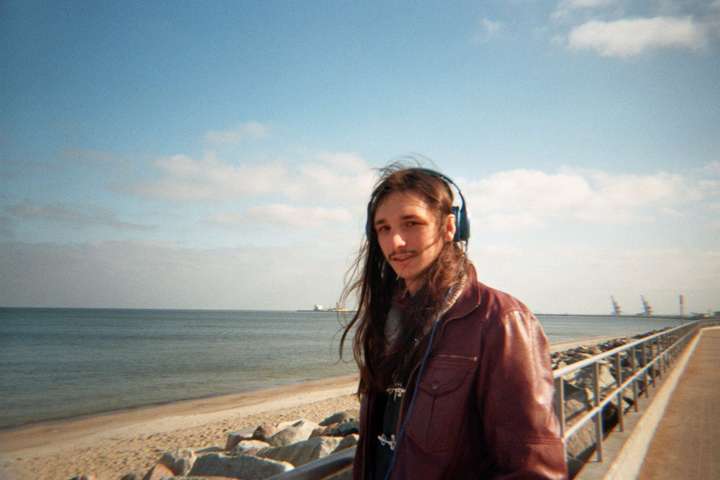 A man at the beach in a red leather jacket