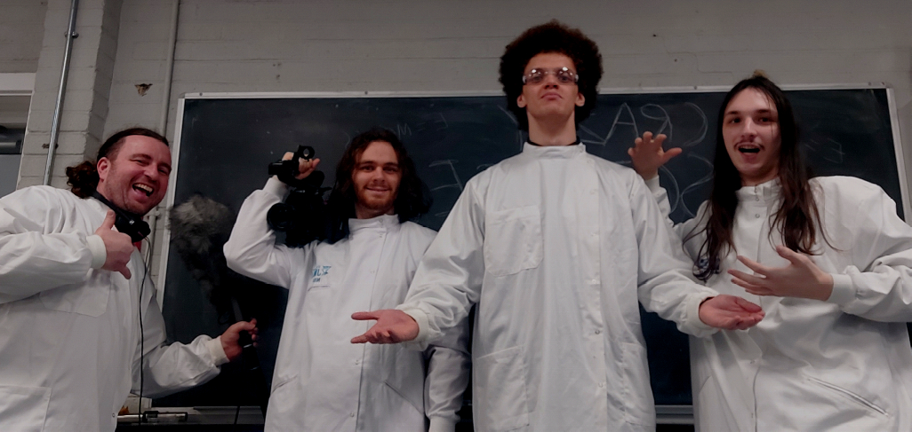 Four men in white lab coats in front of a blackboard