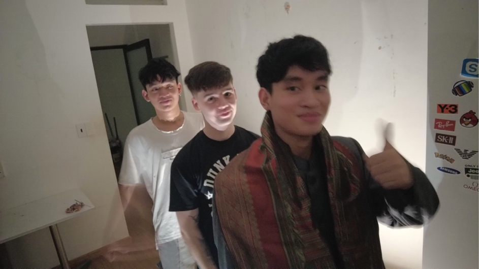 Three men in a line. The one in front isgiving a thumbs up.